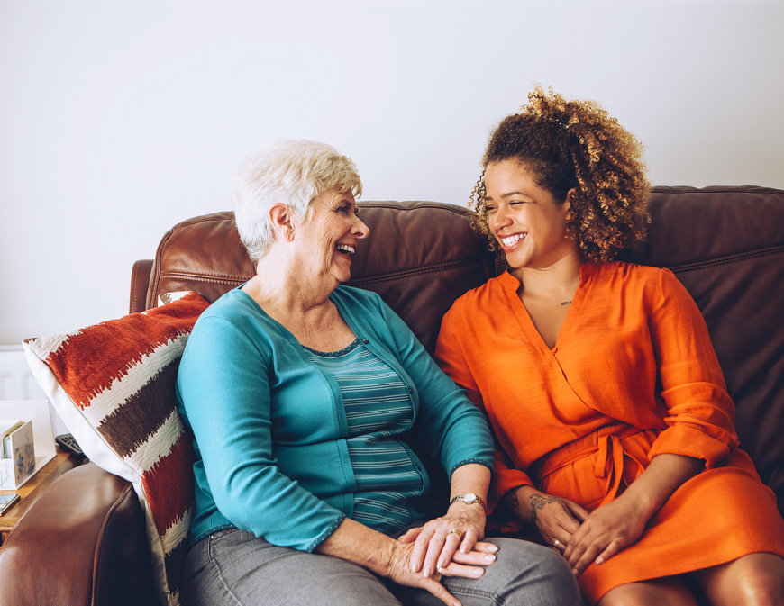 lady and old woman sitting on couch laughing