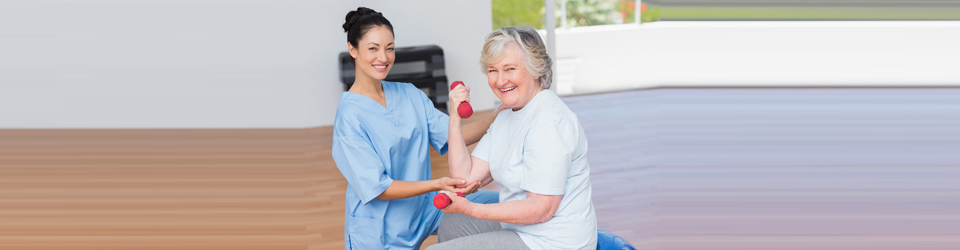 caretaker helping old woman with dumbells